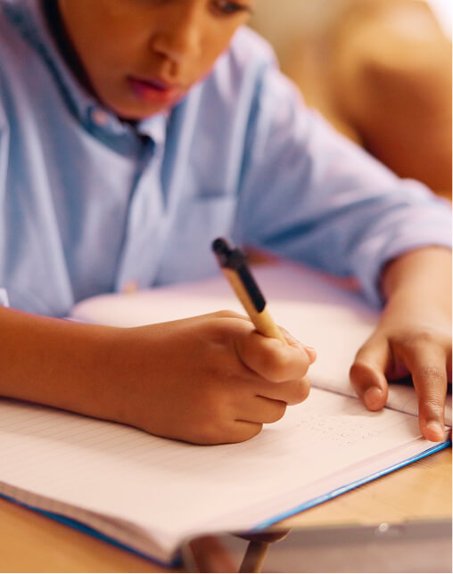 A child writes in an exercise book with a pen, focusing on turning ideas into a story after using Pobble Home. A child writes in an exercise book with a pen, focusing on turning ideas into a story after using Pobble Home.